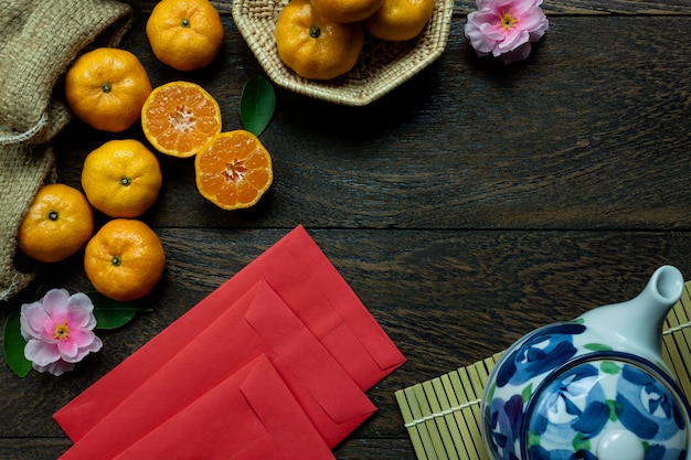 Accessoires de vue de dessus décorations de festivals chinois. Nouvel an, feuille, panier en bois, paquet rouge, fleur de prune, théière sur fond de table en bois.