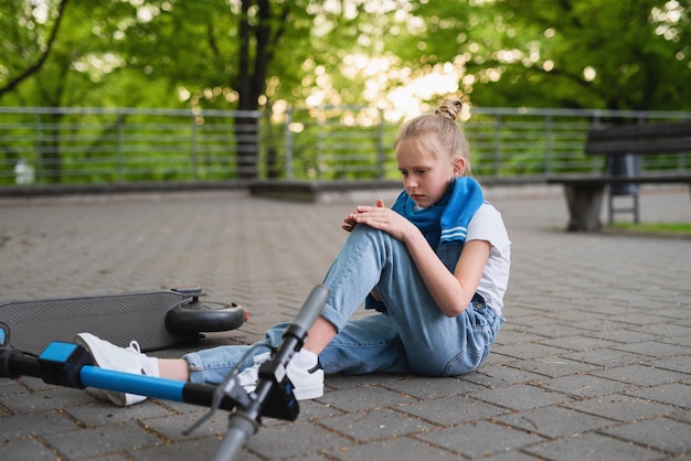 Accident de scooter électrique - fille souffrant de douleur après une blessure au genou dans le parc de la ville