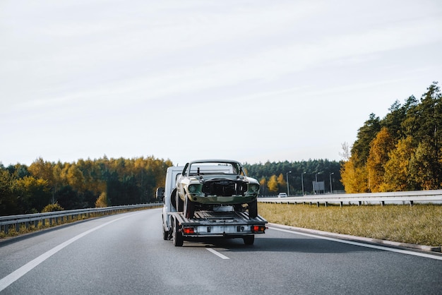 Photo un accident de voiture sur l'autoroute conduit à l'arrivée d'une dépanneuse le transporteur ramasse la voiture détruite et l'emporte le ciel est nuageux et la circulation est lente