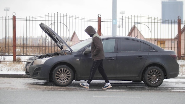 Photo un accident de voiture un jeune homme marchant par une voiture cassée