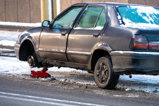 Accident de voiture sur la route en hiver Le conducteur change la roue sur la route dans la ville dans le froid dans des conditions difficiles Conditions routières dangereuses dans des conditions glaciales