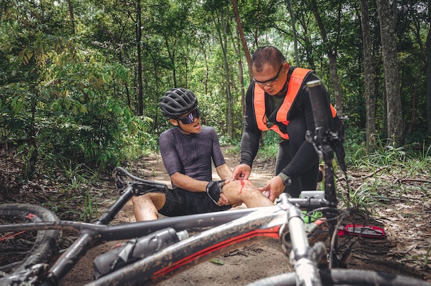 Accident de VTT et premiers secours : Accident de motard, blessure au genou et à la jambe, Premiers secours pour aider le vététiste accidenté. L'équipe de premiers soins d'athlète de vélo de montagne a été blessée lors d'un accident de course.