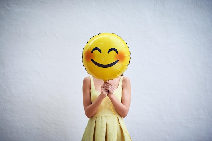 Photo accrochez-vous à votre sourire et répandez le bonheur prise de vue en studio d'une jeune femme tenant un ballon avec un smiley devant son visage