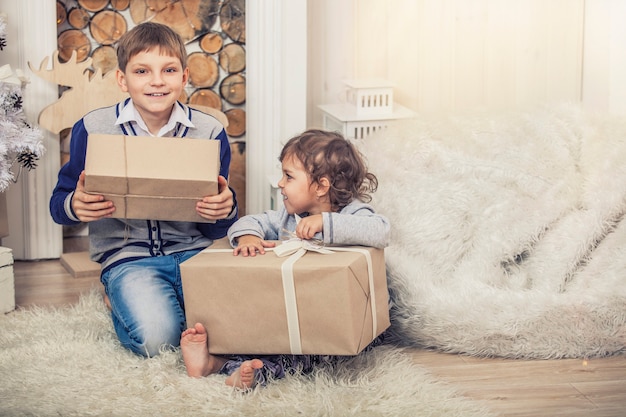 Accueil un garçon et une fille heureux avec des boîtes de cadeaux à l'intérieur de Noël