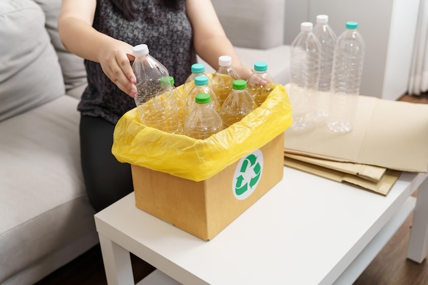 Accueil recycler eco vert zéro concept Femme jetant une bouteille en plastique vide dans un bac de recyclage avec des sacs à ordures jaunes à la maison