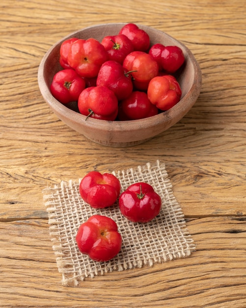 Acérolas ou cerises de la Barbade dans un bol sur une table en bois