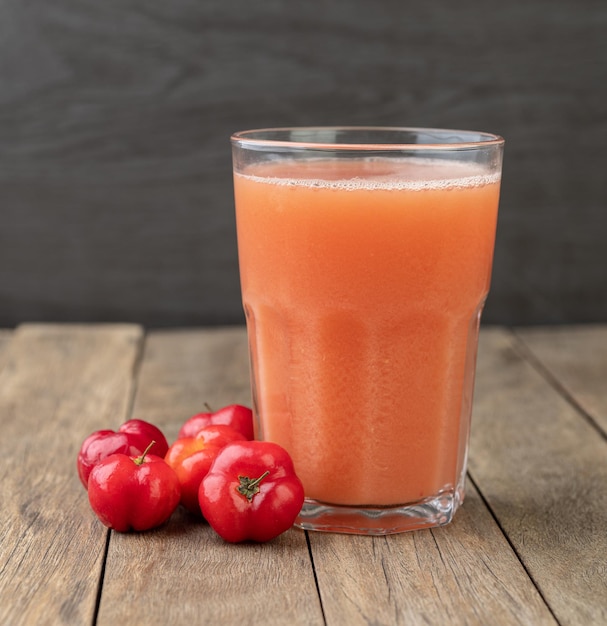 Acérolas ou jus de cerises de la Barbade avec fruits sur table en bois