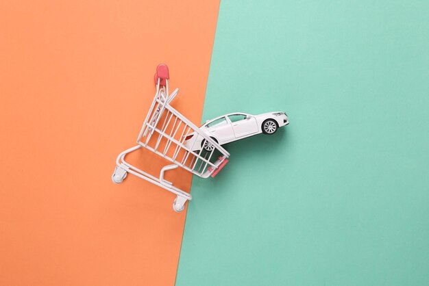 Photo achat d'un concept de voiture chariot d'achat avec modèle de voiture jouet sur fond bleu rose vue supérieure