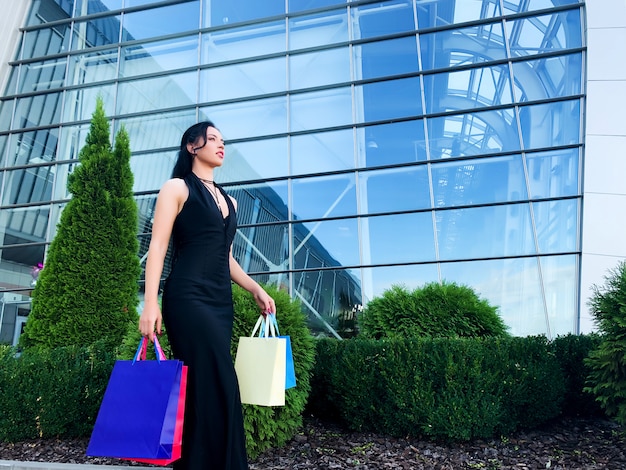 Achats. Femme tenant des sacs colorés près de son centre commercial en noir vendredi vacances