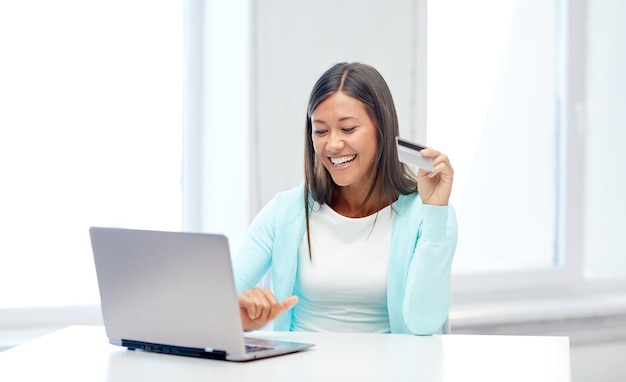 achats en ligne, concept de personnes et de technologie - jeune femme souriante avec ordinateur portable et carte de crédit à la maison ou au bureau