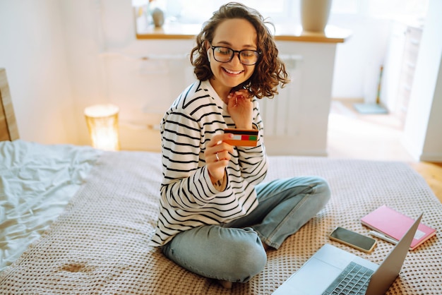 Achats en ligne à la maison Une jeune femme détient une carte de crédit et utilise un ordinateur portable Vente du vendredi noir