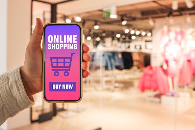 Achats en ligne Téléphone en main avec l'application du site acheter en ligne sur fond de magasin de vêtements