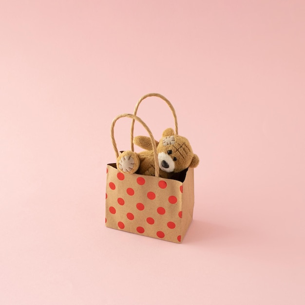 Photo acheter du bonheur et de l'amour ours en peluche dans un sac cadeau concept créatif minimal sur fond rose