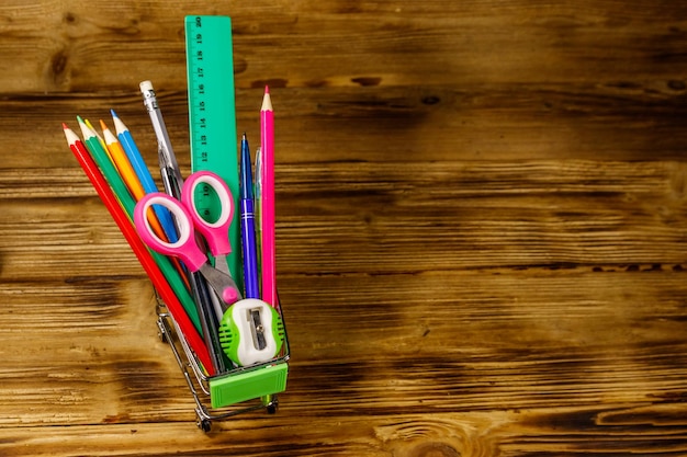 Acheter des fournitures scolaires Panier avec des fournitures scolaires sur un fond en bois Concept de retour à l'école