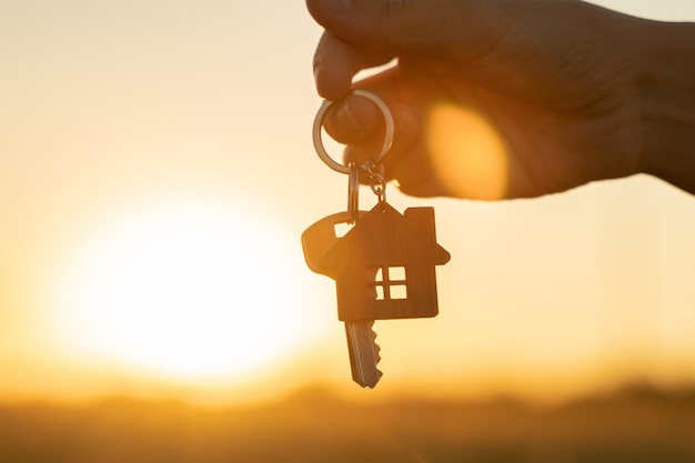 Acheter ou louer un concept de maison d'habitation une main de femme tient une clé avec un porte-clés en forme de...