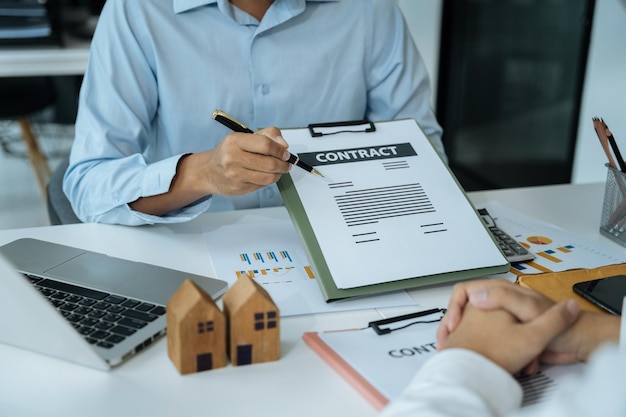 Acheter une maison ou un contrat d'assurance un agent d'assurance pointant un stylo vers les personnes intéressées par la location d'une maison un contrat signant un contrat d'achat de maison au bureau