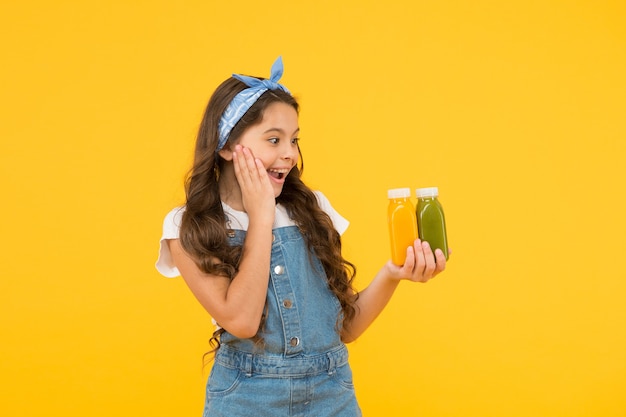 Acheter de la nourriture. Promotion de supermarché. Vivre une vie saine. Jus vitaminé. Smoothie frais. Fille buvant un smoothie frais à l'orange. Notion végétarienne. Un enfant souriant tient des bouteilles de smoothie aux fruits. Nourriture saine.