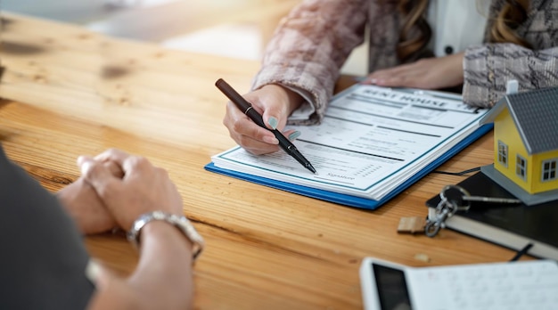 Les acheteurs de maisons rencontrent et négocient avec des agents immobiliers au sujet de la location d'une maison et demandent au client de signer un contrat