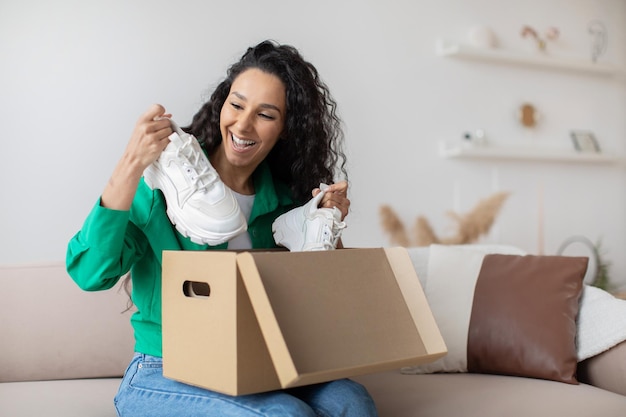 Acheteuse heureuse déballant une boîte en carton avec des chaussures livrées à l'intérieur