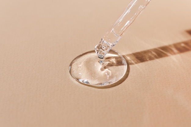 Photo acide hyaluronique dans une pipette en verre sur fond beige sérum transparent