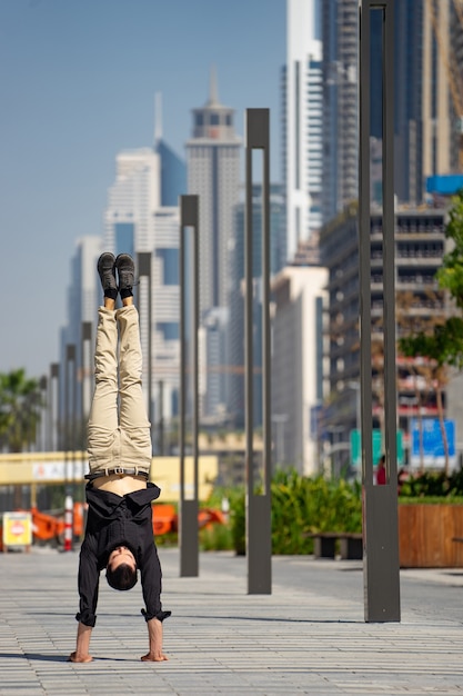 Acrobat garde l'équilibre entre les mains avec le paysage urbain flou de Dubaï. Concept de possibilité moderne, commerciale et illimitée.