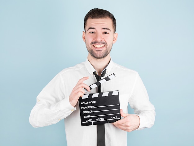 Acteur masculin professionnel prêt pour le tournage du film, détient le battant de film, sur le bleu.