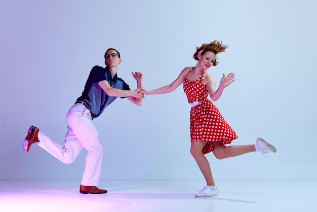 Actif charmant jeune homme et femme en costumes colorés dansant des danses de style rétro contre