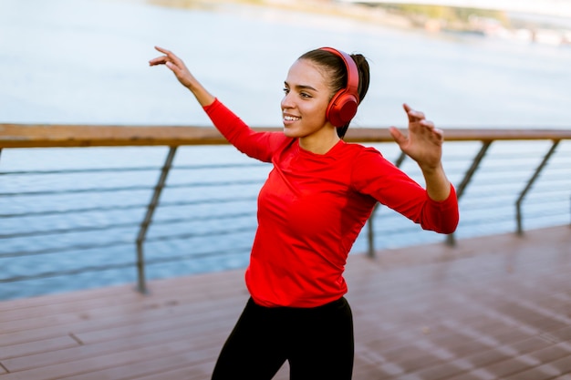 Actif jeune belle femme qui court sur la promenade le long de la rivière