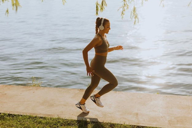 Actif jeune belle femme qui court sur la promenade le long de la rivière