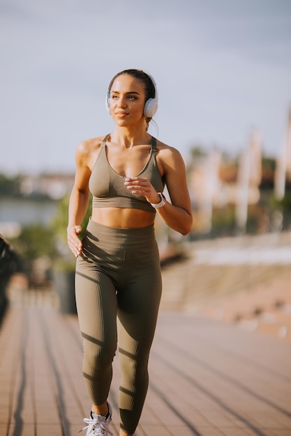 Actif jeune belle femme qui court sur la promenade le long de la rivière