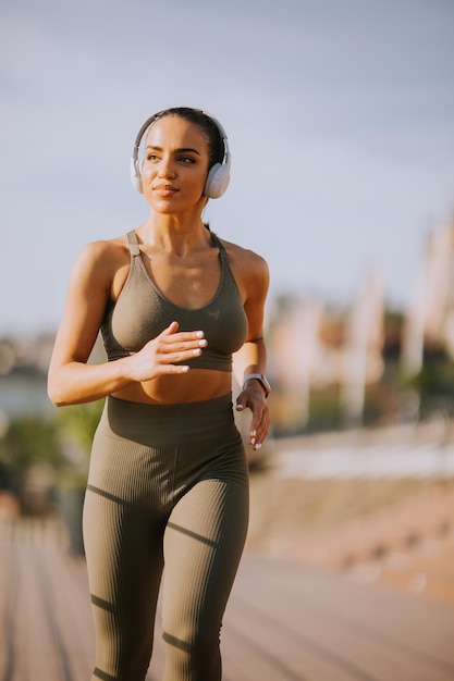 Actif jeune belle femme qui court sur la promenade le long de la rivière