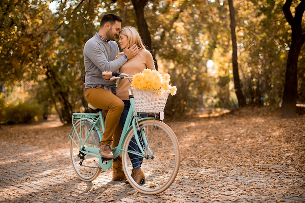 Actif jeune couple jouir ensemble à vélo dans le parc automne doré