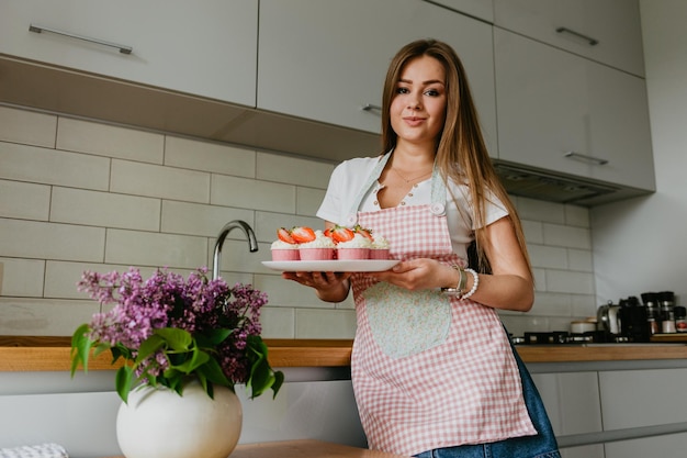 L'action de faire des cupcakes en velours rouge Main de femme ajoutant du sucre saupoudrer sur le cupcake