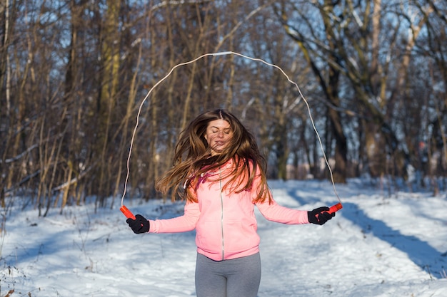 Active jeune femme effectue un exercice avec une corde à sauter