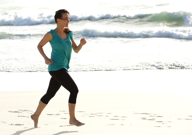 Active jeune femme heureuse qui longe le bord de mer