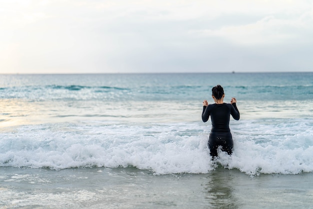 Active jeune mère et fille en maillot de bain jouant à la plage contre le coucher du soleil en mer.