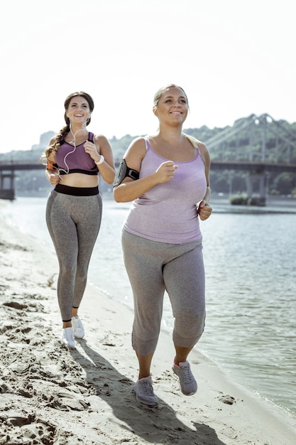Activité cardio. Heureuses femmes actives profitant de leur formation en faisant du jogging près de la rivière