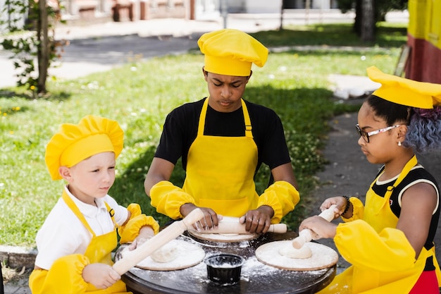 Activité de cuisinier d'enfance d'enfants multinationaux d'enfants noirs africains et caucasiens Bonne compagnie d'enfants multiethniques cuisinant de la pâte