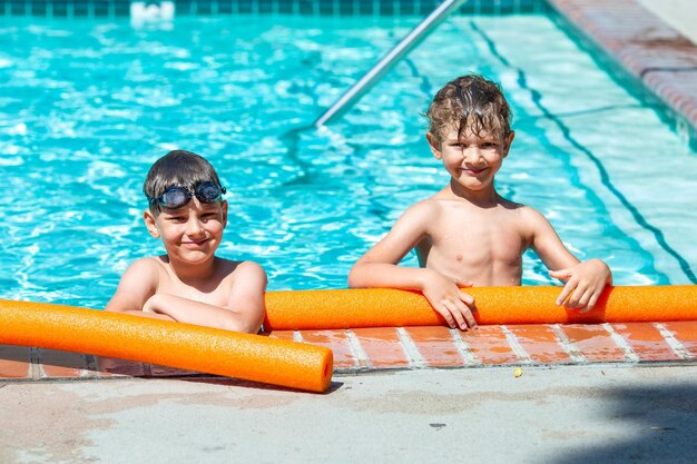 Photo activité d'été en plein air concept de santé et de vacances amusantes des garçons heureux de huit et cinq ans portant des lunettes de natation se tiennent au bord de la piscine par une chaude journée d'été