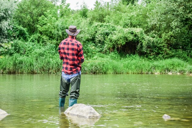 Activité de passion Week-end d'été de pêche à la mouche réussi pêcheur expérimenté dans l'eau pêcheur montrer la technique de pêche utiliser la canne activité sportive et passe-temps homme attraper du poisson homme mûr pêche à la mouche