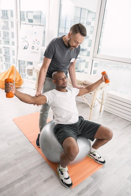 Activité physique. Bel homme fort penché en arrière tout en faisant un exercice sur le medball