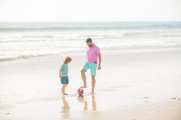 Activité sportive père et fils jouent au football sur la plage papa avec enfant garçon