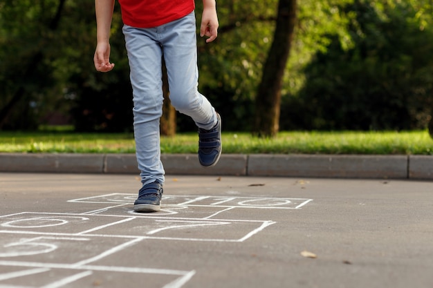 Activités estivales pour les enfants. Garçon jouant à la marelle.