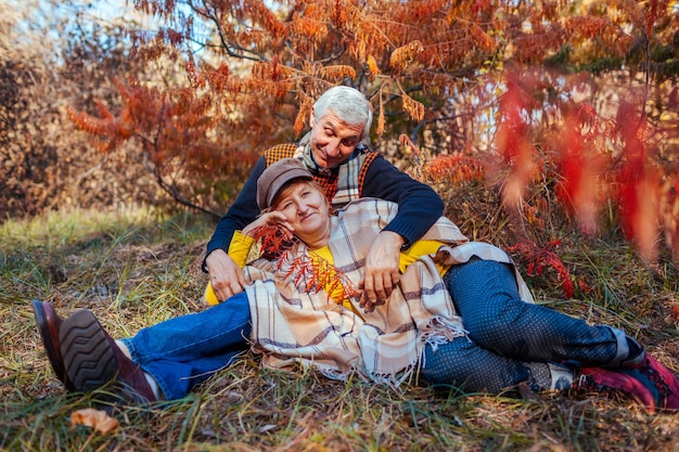 Photo activités familiales d'automne un couple de personnes âgées se détend dans le parc d'hiver allongé sous un arbre les gens apprécient la nature