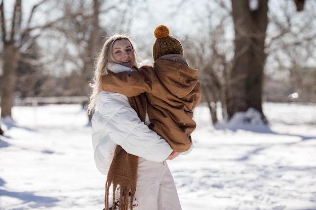 Activités familiales en plein air pour de bonnes vacances d'hiver Une mère heureuse et ses deux fils jouant aux boules de neige dans une rue enneigée de la banlieue Une famille heureuse le week-end d'hivers Fêtes de Noël