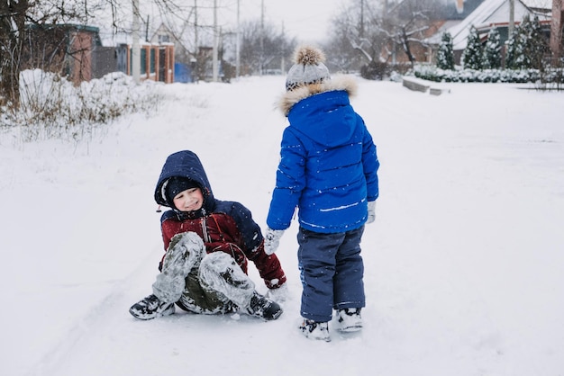 Activités hivernales en plein air pour les enfants jouant dans la cour d'hiver de la banlieue rassemblant des garçons ayant