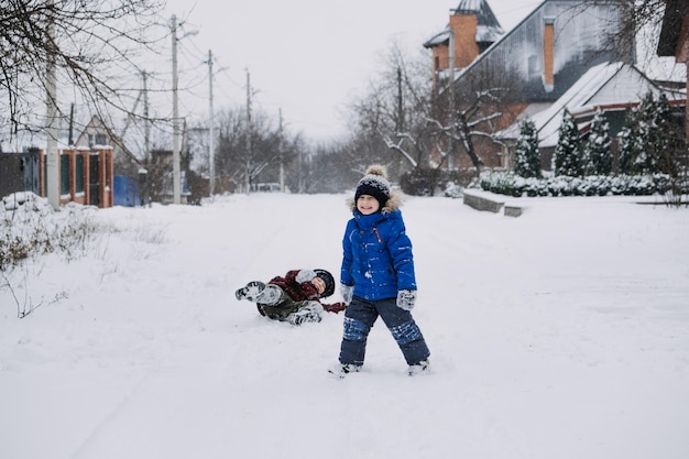 Activités hivernales en plein air pour les enfants qui jouent dans la cour d'hiver de la banlieue rassemblant deux garçons