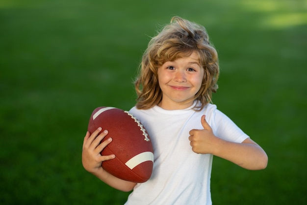 Activités sportives pour enfants en plein air garçon américain jouant au football américain ou au rugby dans le parc enfants sportifs