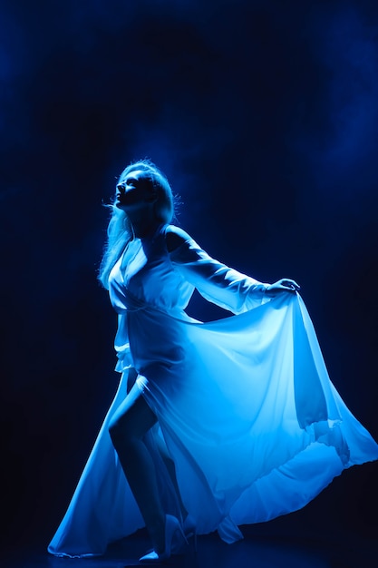 Actrice / chanteuse sur scène sous les rayons de la lumière bleue.