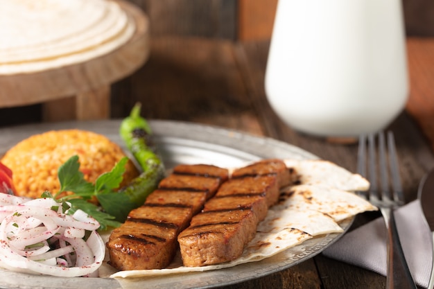 Adana Kebap turc avec riz pilaf et légumes servis sur une assiette